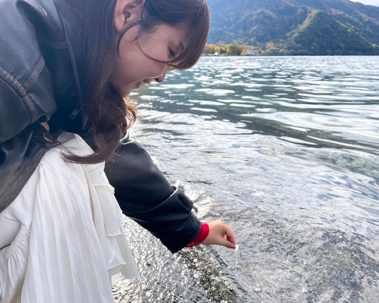 よったおより紙を十和田湖へ投げ入れる