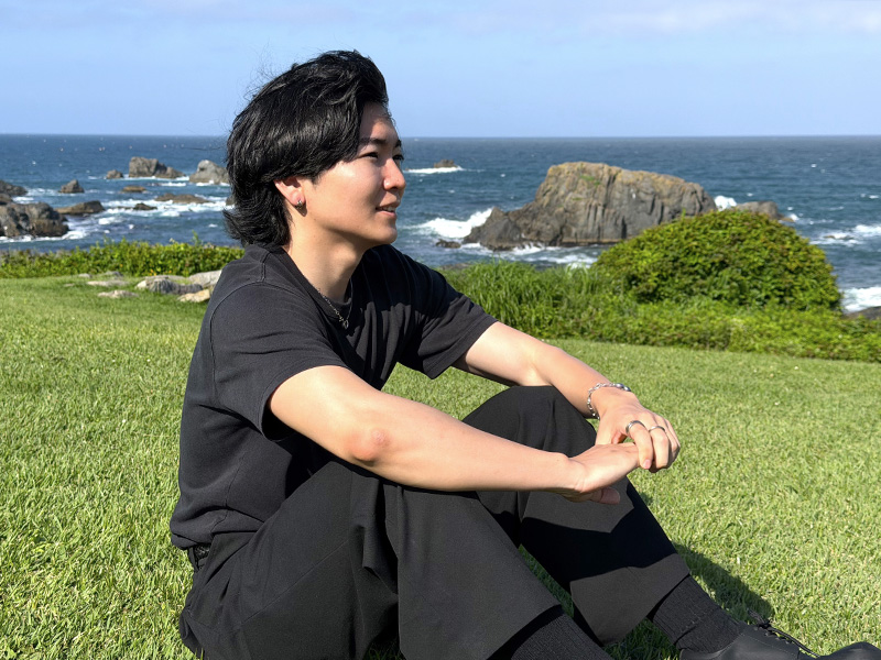海を望む草原でくつろぐ豊川さん
